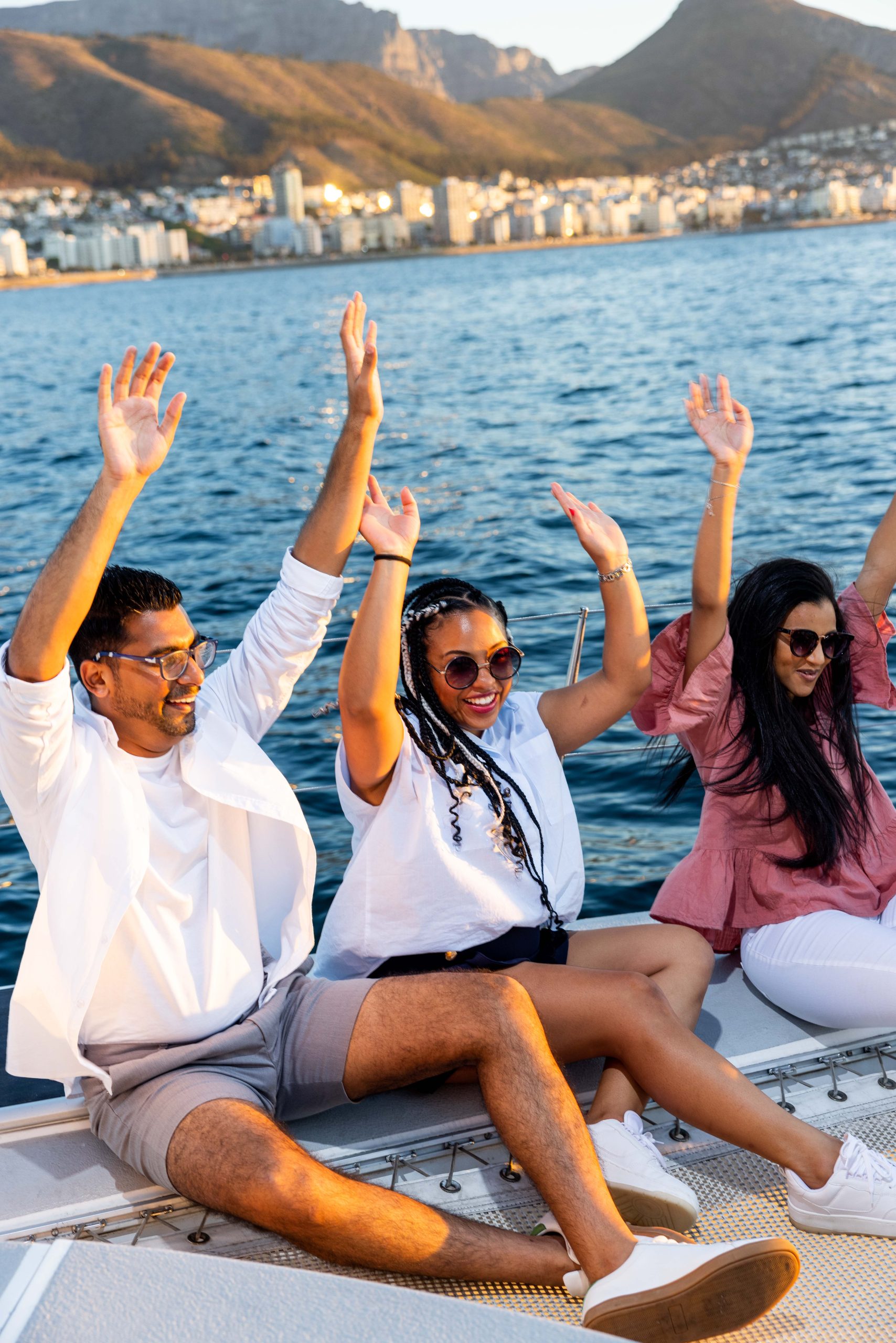 Events and Special Offers Three people sitting on a boat with raised arms, enjoying a sunny day on the water.
