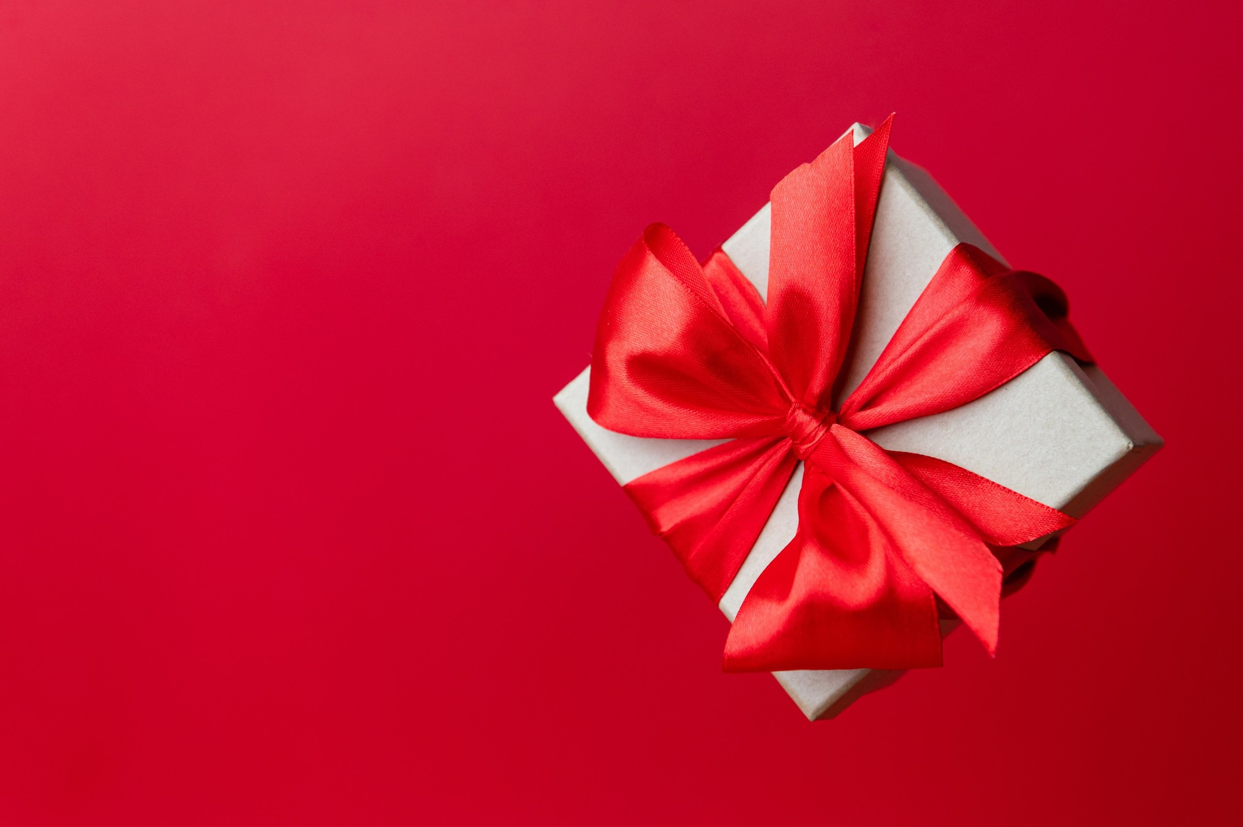 Gift box with red ribbon on a red background.