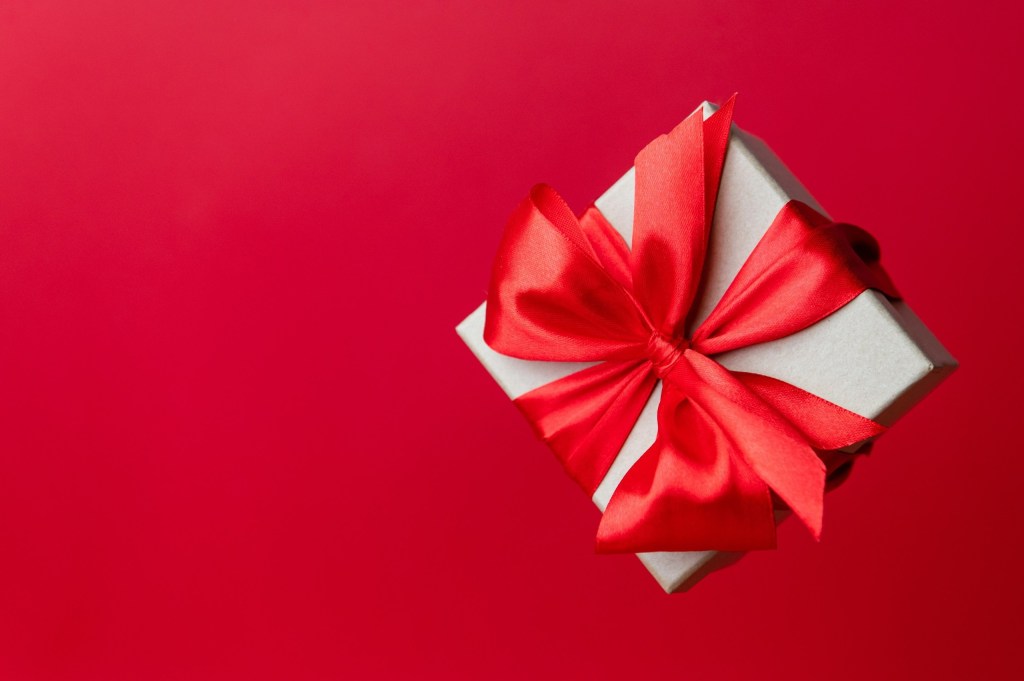 Gift box with red ribbon on a red background.