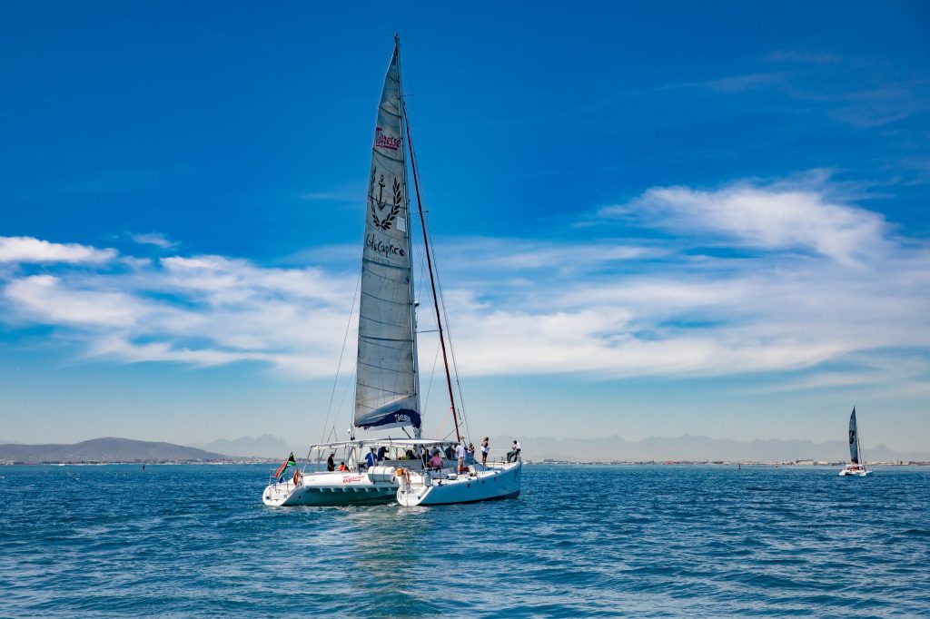 Sailboat with tall mast on calm blue sea under clear sky.
