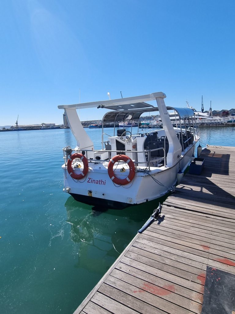 Boat docked at a pier with clear blue sky and water.