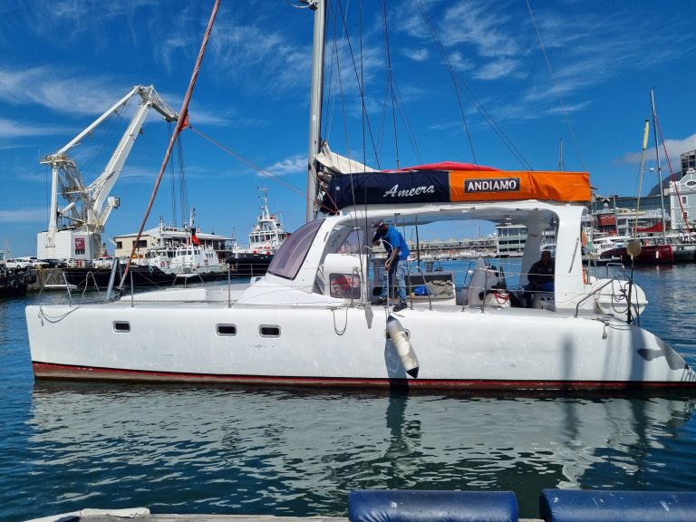 White sailboat docked in a harbor under a clear blue sky.