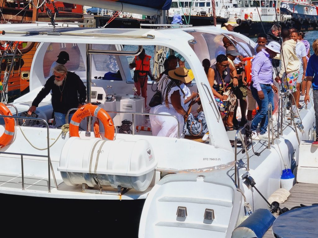 Group of people on a docked boat with colorful clothing and safety gear.