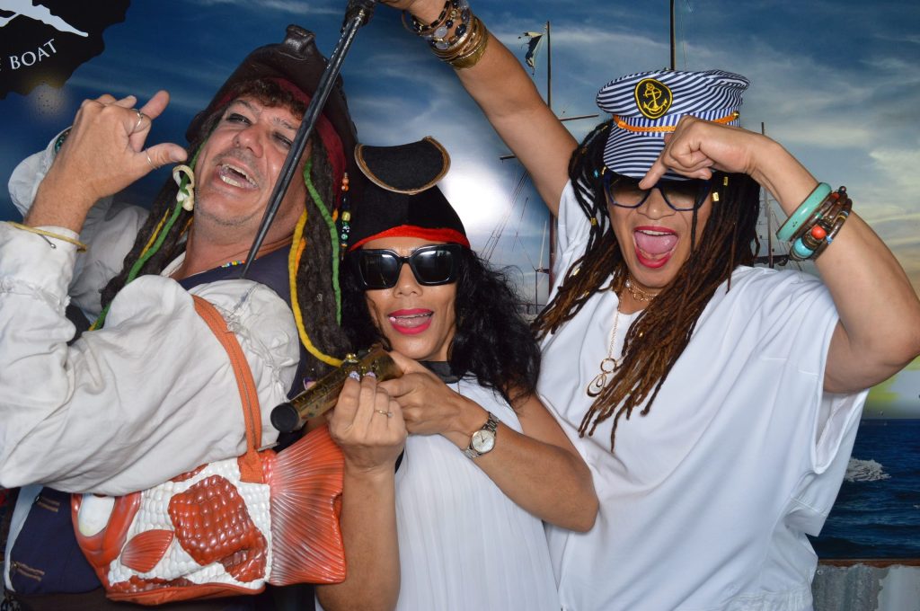 Three people dressed in whimsical pirate costumes, posing playfully with a toy sword.