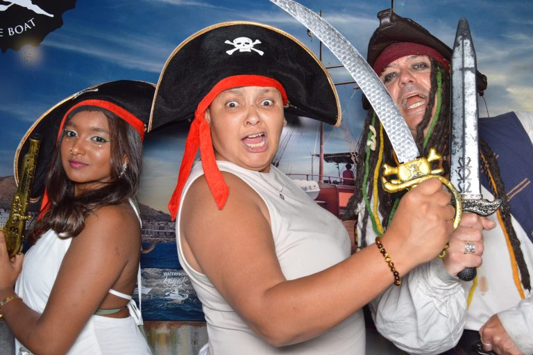 Three people dressed as pirates with hats and swords, posing energetically.