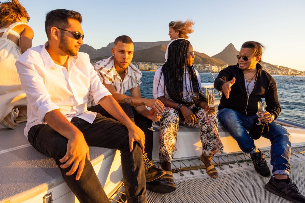 Four people sitting on a boat at sunset with mountains in the background.