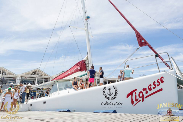 Catamaran 'Tigresse' docked with people on deck under blue sky.