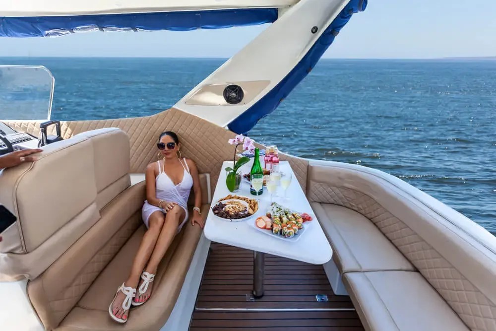 Woman lounging on yacht with food and ocean view.