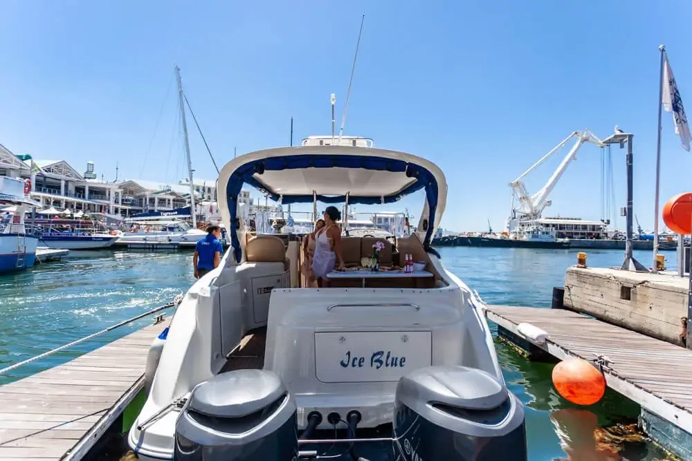 Motorboat docked with people on board at a marina on a sunny day.